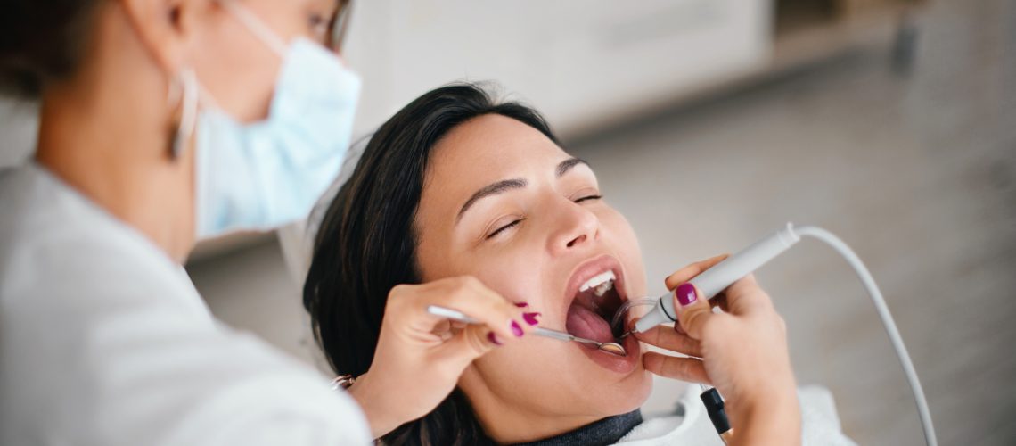 Dentist removing dental calculus from the patient in the dental office.