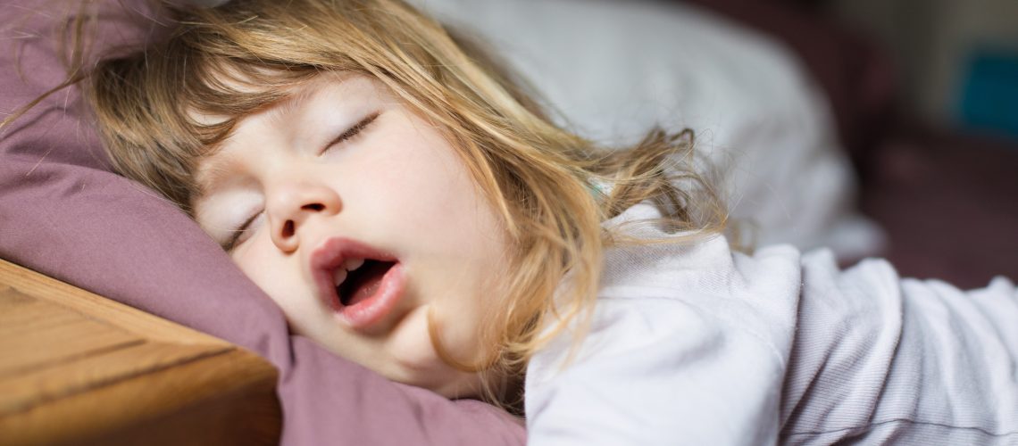 funny face expression with open mouth of blonde caucasian three years old child,  sleeping on  king bed